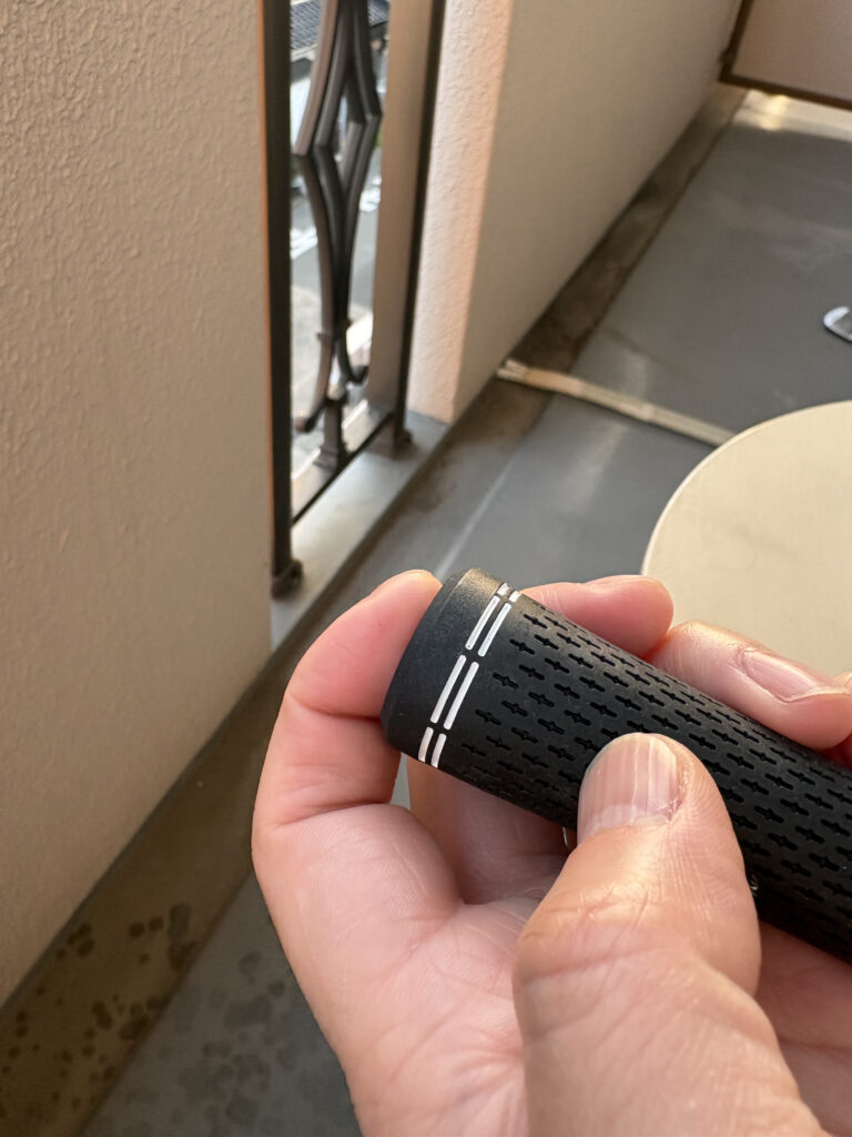 溶剤を注入したゴルフグリップの端を親指でしっかり塞ぎ、液を全体に行き渡らせるために手で持っている様子