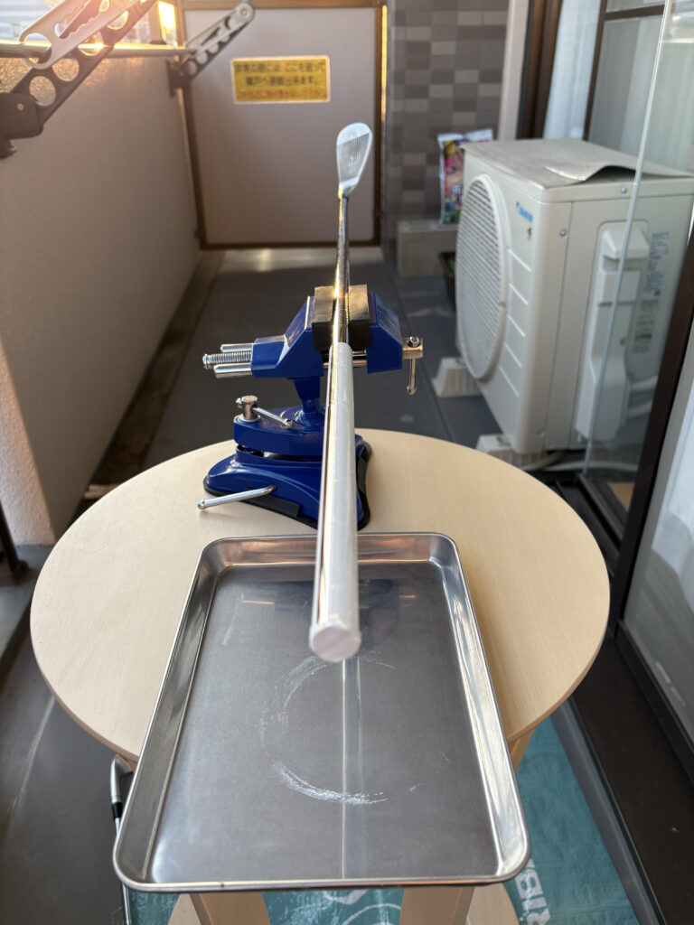 ベランダに設置した万力でゴルフクラブを水平に固定し、下に溶剤受けのトレイを置いて作業準備を整えた様子