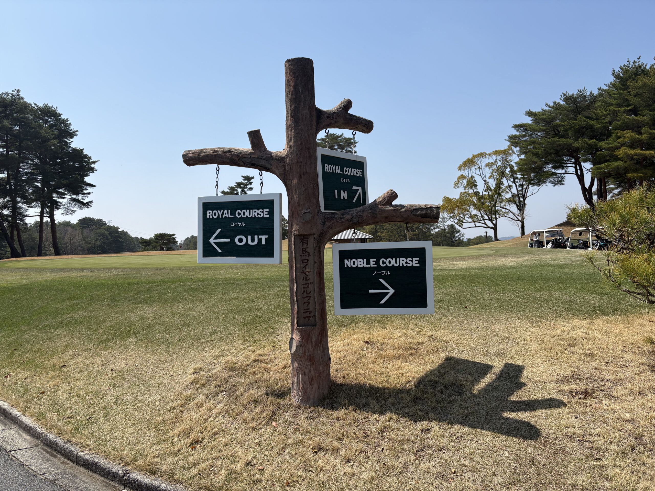 有馬ロイヤルゴルフクラブのコース分岐点に設置された、木製の標識。左が「ROYAL COURSE (ロイヤル)」のOUT/IN、右が今回予約した「NOBLE COURSE (ノーブル)」を指している。