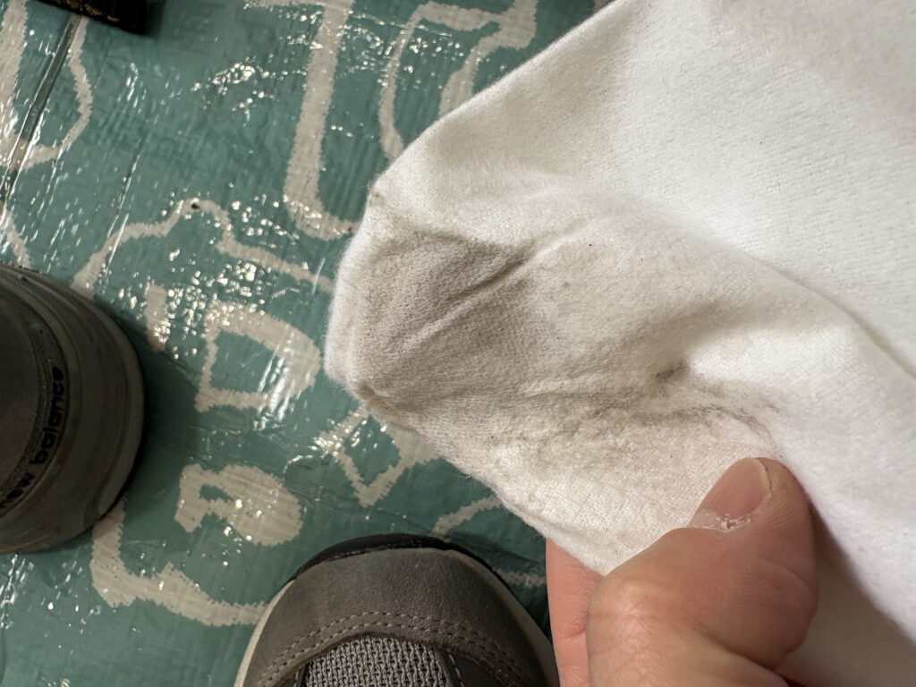 New Balance 993のスエード部分をメンテナンスした後の白いタオルに、黒ずんだ汚れがびっしりと付着している様子。
